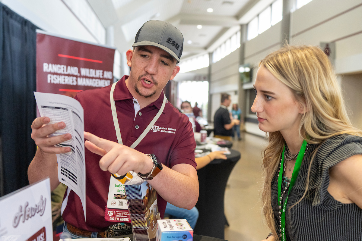 A 2025 Texas 4-H Roundup participant talking to an individual about the Department of Animal Science.